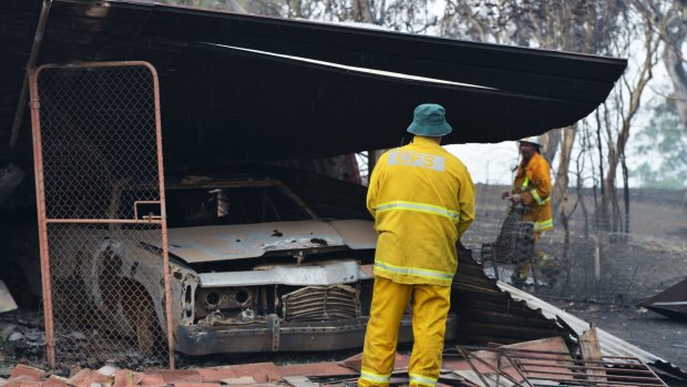 Country Fire Service volunteers work next to a burnt out shed near One Tree Hill in the Adelaide Hills on Saturday. 
