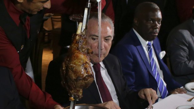 Brazilian President Michel Temer, centre, alongside Angola's ambassador to Brazil, Nelson Manuel Cosme, dine at a traditional Brazilian barbecue restaurant after a meeting on the rotten meat scandal in Brasilia on Sunday.