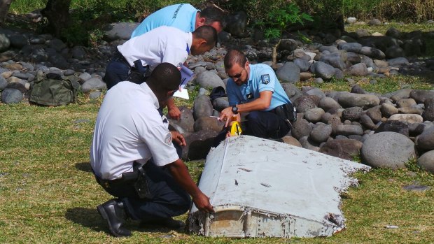 French police inspect a large piece of plane debris that was found on the beach in Saint-Andre, on Reunion Island in July.