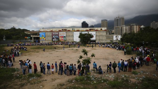 Shoppers queue outside a supermarket in Caracas. 