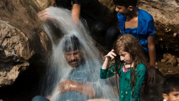 A family cools off in a stream during a heat wave last month in Islamabad, Pakistan.