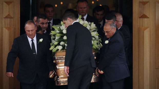 Tony Sergi's gold coffin, covered in white flowers, is taken out of the Sacred Heart Catholic Church on Friday.