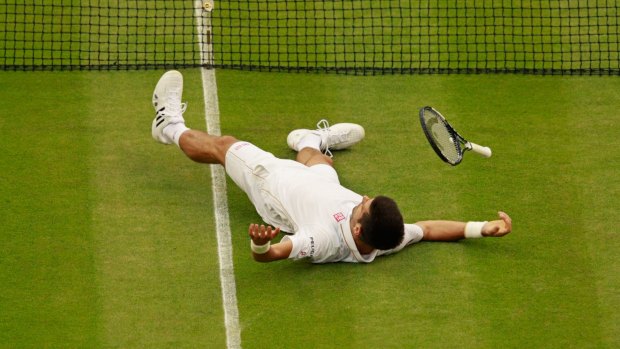 Novak Djokovic lays on the floor after playing a shot at Wimbledon.