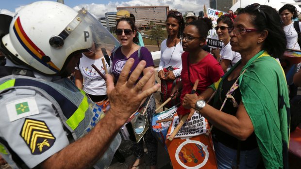 A policeman turns away a group of women hoping to join a march in Brasilia supporting a general strike, because the instruments they were carrying could be used as weapons.