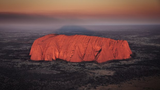 Uluru glowing at sunrise during a helicopter tour.