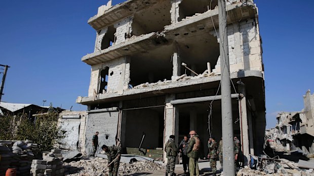 Pyrrhic victory: Russian and Syrian army soldiers gather at the last checkpoint before the front line in Karam al-Tarab, east of Aleppo, earlier this month.