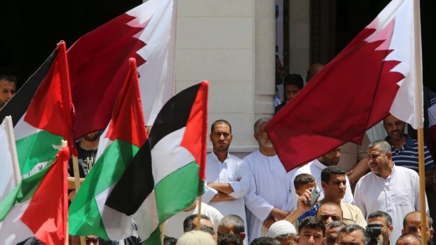 Palestinians in the Gaza Strip wave their national flag and the flag of Qatar during a demonstration in solidarity with the people of Qatar after the sanctions were announced.