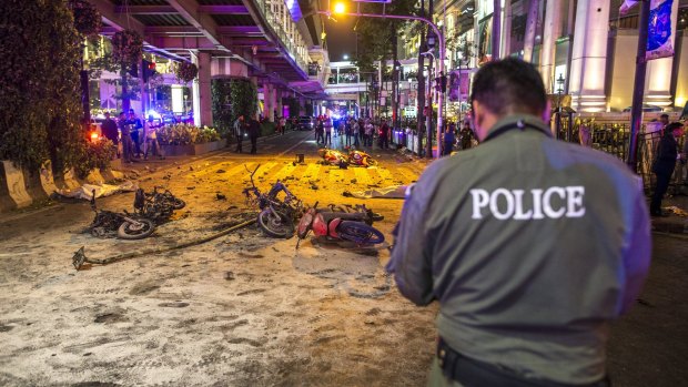 Bodies of victims are covered with white sheet among wreckages of motorcycles and other debris as security forces and emergency workers gather at the scene of the blast in central Bangkok.