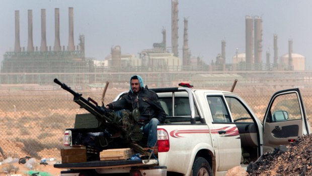 A rebel sits with an anti-aircraft weapon in front of an oil refinery in Ras Lanouf, eastern Libya. 