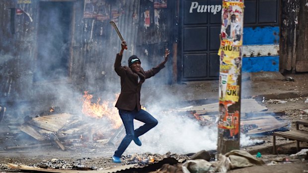 A man brandishing a "panga" machete challenges policee in the Mathare slum of Nairobi.