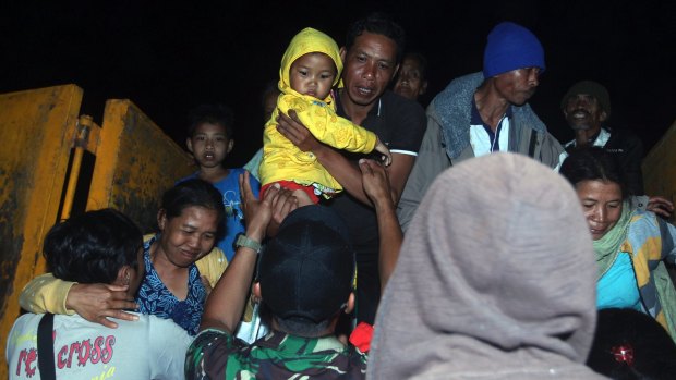 Rescuers assist villagers who were evacuated from their homes on the slope of Mount Agung.