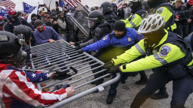 Trump supporters try to break through a police barrier outside the Capitol Building in Washington DC.