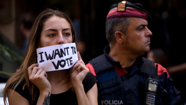 A demonstrator covers her mouth next to a Catalan police officer in Barcelona.