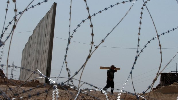 A Palestinian man walks next to a section of the wall being built near the occupied West Bank village of Masha in 2003.