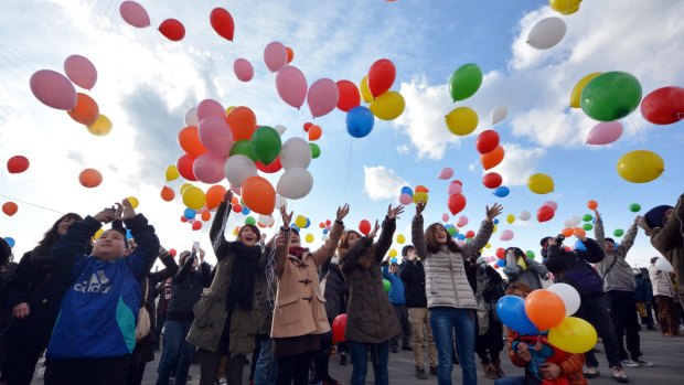 Bereaved families, relatives and friends release balloons as they visit Arahama Beach.