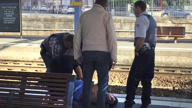 French police stand over Ayoub el Khazzani, who was apprehended on the platform at the Arras train station after being restrained on the Amsterdam to Paris Thalys high-speed train on Friday.