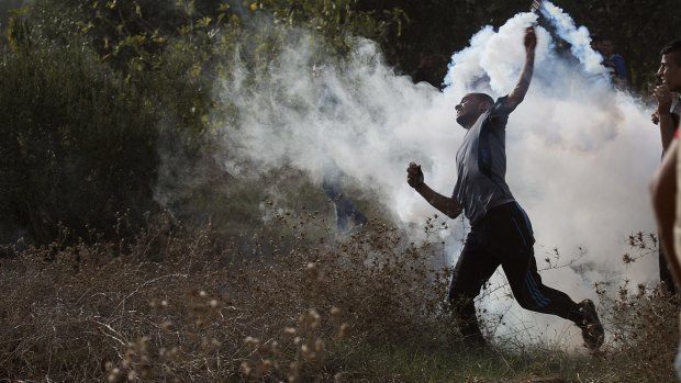 A Palestinian protester throws back a tear gas canister during clashes with Israeli soldiers by the Israeli border with Gaza, east of Bureij refugee camp, on Friday. 