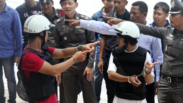 The two Myanmar men, in helmets and handcuffs, charged in the killings, were made to take part in a re-enactment of the crime.