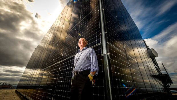 Engineering services manager Bill Burgess next to the solar panels near the top of 101 Collins.