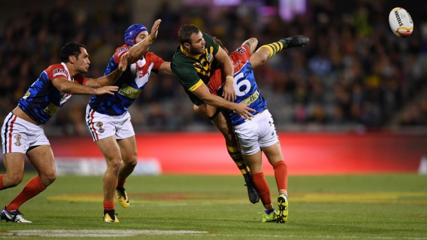 Wade Graham of the Kangaroos (centre) passes a ball as he is tackled by Remy Marginet of France.