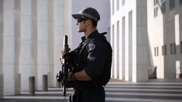 An AFP officer armed with an SR-16 stands guard to the front of Parliament House.