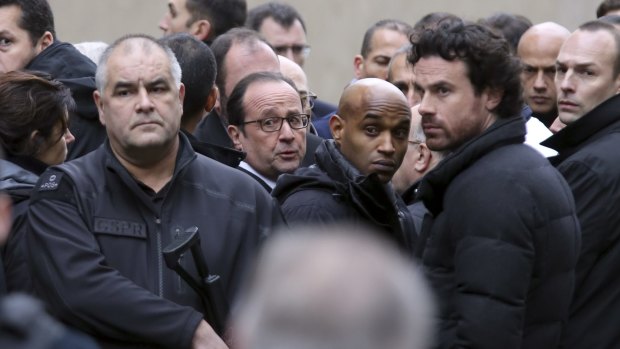 French President Francois Hollande, centre, flanked by security forces arrives at the office of satirical magazine <i>Charlie Hebdo</i> in Paris.