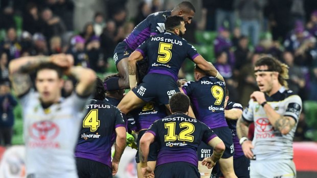 Brodie Croft is swamped by his Melbourne Storm teammates after kicking the winning goal against the Cowboys on Saturday night.