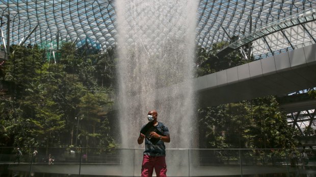 A tourist wears a protective mask near the Rain Vortex at the Jewel Changi Airport.