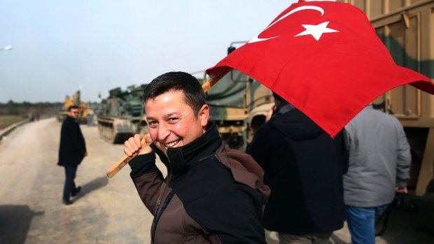 A civilian holding a Turkish flag arrives to encourage the troops at a Turkish army area on the border with Syria.