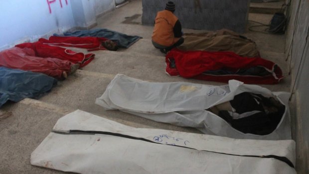 A worker arranges bodies collected in a building in eastern Aleppo on Tuesday. Officials say they are struggling to find places to bury the dead.
