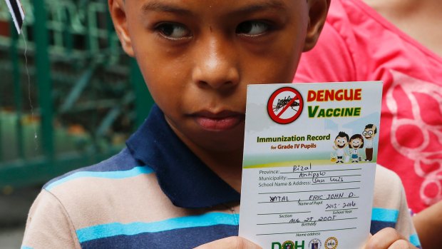 Eric John Vital, 12, holds his vaccination record as he joins other protesters demand accountability at a rally outside the Department of Health in Manila.
