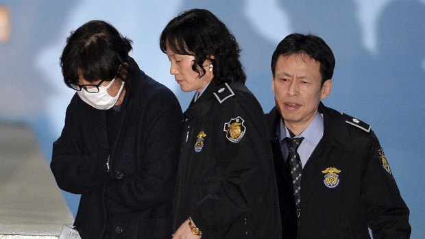 Choi Soon-sil,  left, is escorted onto a bus  as she left the Seoul Central District Court on November 3.