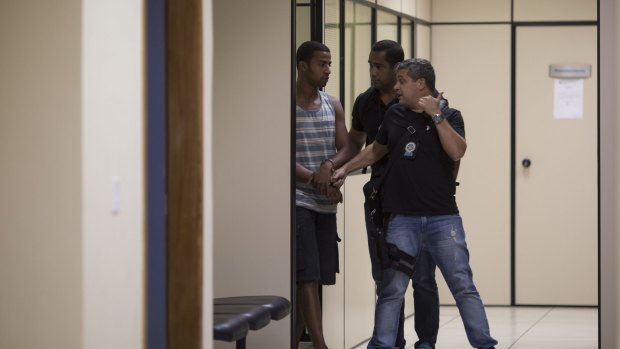 Gang rape suspect Rai de Souza, 22, is escorted by officers at a police station in Rio de Janeiro on Monday.
