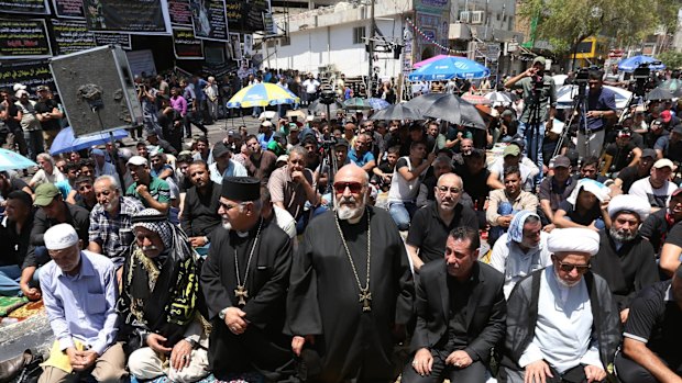 Christians, Sunnis and Shiites pray together at the scene of a massive truck bombing by the Islamic State group in Baghdad, Iraq, this month.