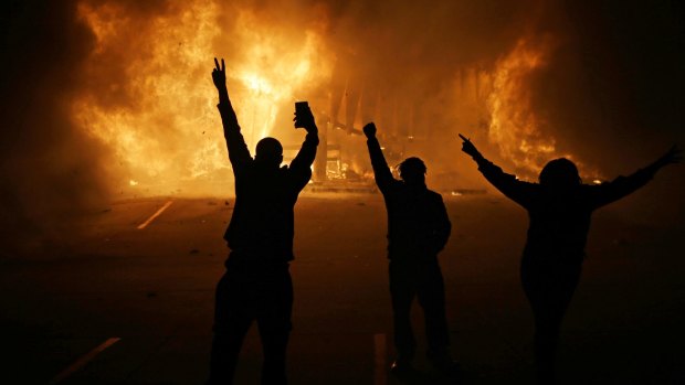 People watch as stores burn in Ferguson in November 2014 after the fatal police shooting of Michael Brown.