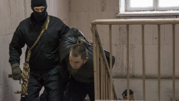 Police escort Tamerlan Eskerkhanov, one of five suspects in the killing of Nemtsov, into court on Sunday.