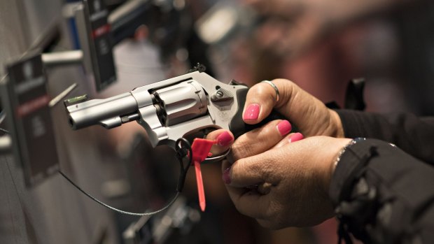 A woman handles a gun at the National Rifle Association annual show in Nashville in April.