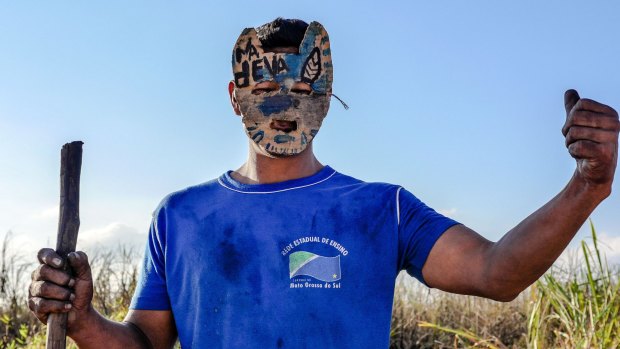 A masked gatekeeper guards a blocked road to Yvu Farm in the aftermath of Santos' death.