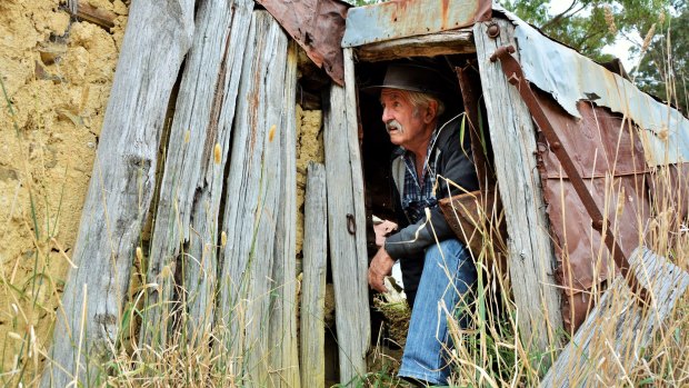 Peter Firth crawls out of the remains of "Ted's Hut" on the outskirts of Gundaroo.