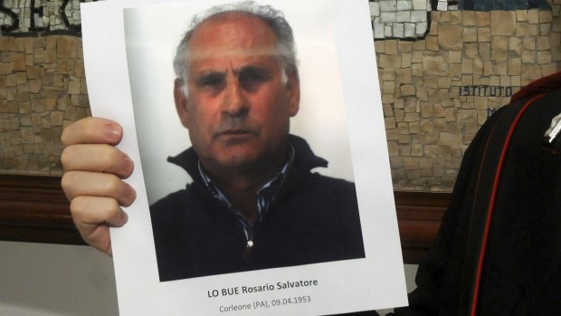An Italian Carabiniere holds a picture of arrested Mafia boss Giuseppe Lo Bue during a press conference in Palermo, Italy, on Friday.