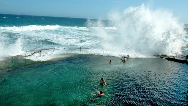 Swimmers watch as waves crash over Bogey Hole.