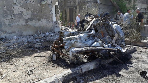 This photo released by the Syrian official news agency SANA, shows people gathering at the scene of an explosion along the road to the airport in southeast Damascus, Syria, Sunday, July 2, 2017.