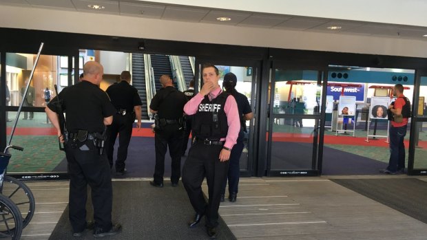 Police officers gather at Bishop International Airport after the attack.