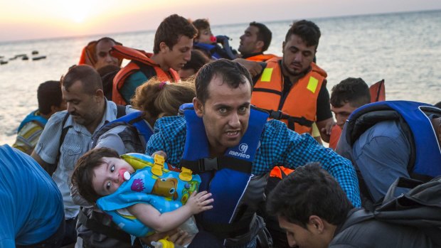 A man carries a girl as migrants arrive on a dinghy after crossing from Turkey to Kos on Thursday.