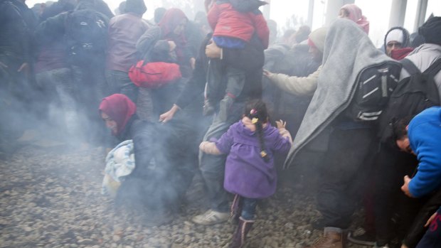 People run away after Macedonian police fired tear gas at a group trying to push their way into Macedonia near the Idomeni on Monday.