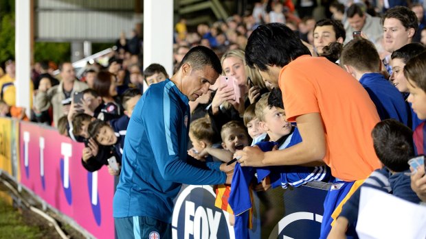 Tim Cahill of Melbourne City signs autographs for fans.