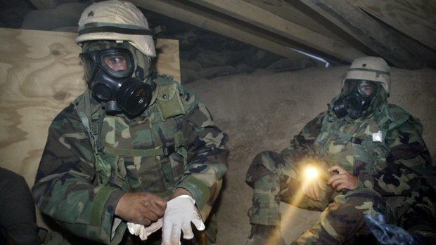 US soldiers in NBC (nuclear, biological, chemical) gear under torchlight in a bunker near camp Doha after a siren sounded a warning for a gas attack in Kuwait in 2003.
