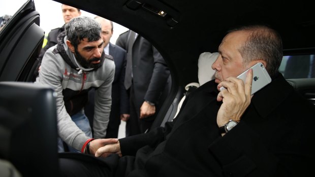 Turkish President Recep Tayyip Erdogan, right, takes Vezir Cakras by the hand while speaking on his mobile phone inside his car stopped on the Bosphorus Bridge in Istanbul on Friday.