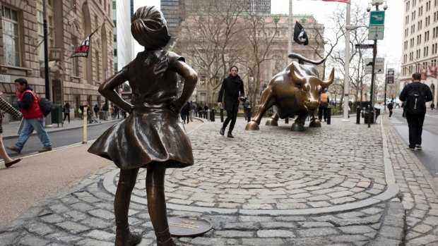 A statue titled "Fearless Girl" faces the Wall Street bull.