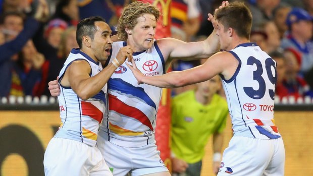 Eddie Betts, Rory Sloane and Riley Knight of the Crows celebrate a goal.